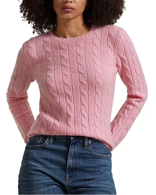 Woman wearing a pink cable knit sweater and blue jeans on a white background