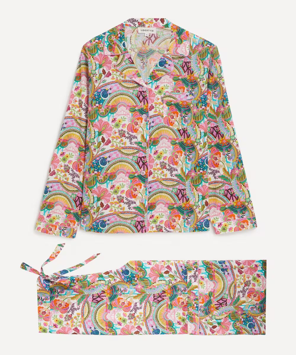 A matching long-sleeve button-front pajama top and tie-side pajama pants set, both featuring a dense multicolor psychedelic print with rainbows, flowers, paisley, and small pink-and-white hearts, shown on a light gray background.