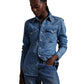 Person wearing a blue denim shirt and jeans on a white background