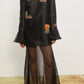 Woman wearing a black dress with floral embroidery on a white background