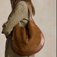 Woman holding a brown leather bag against a beige background