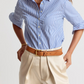 Woman wearing a blue and white striped shirt with beige pants on a light background