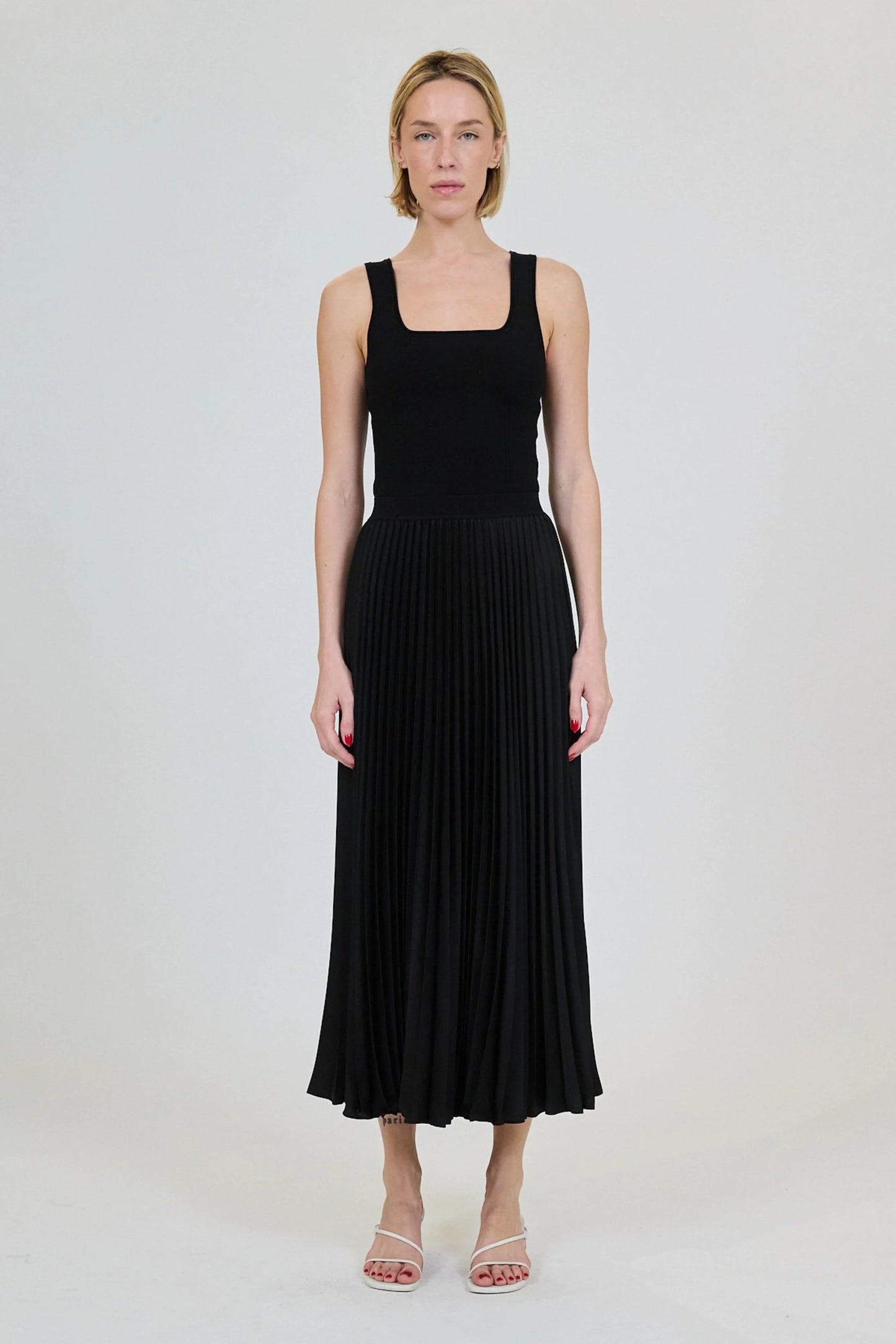Woman wearing a black pleated dress on a white background